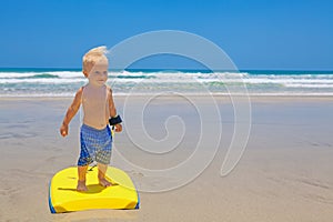 Little child swimming with bodyboard on the sea sand beach