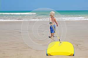 Little child swimming with bodyboard on the sea sand beach