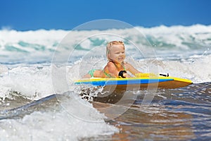 Little child swimming with bodyboard on the sea waves