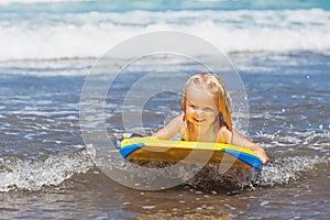 Little child swimming with bodyboard on the sea waves