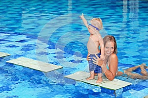 Little child swimming in pool with mother