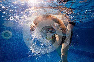 Little child swims underwater in swimming pool