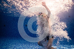 Little child swims underwater in swimming pool