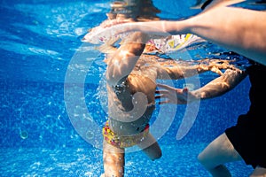 Little child swims underwater in swimming pool