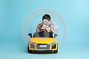 Little child with toy driving car on light blue background