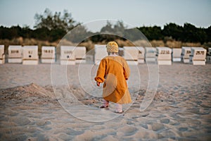 Little child walking on sunset beach on baltic sea among baskets