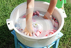 Little child washes clothes in a large basin in retro style