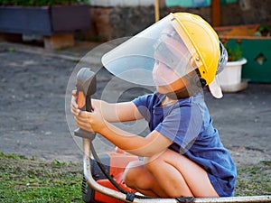 Little child wearing a protective mask with a lawn mower