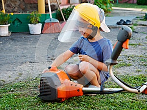 Little child wearing a protective mask with a lawn mower