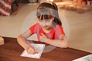 Little child writing letter to Santa at home