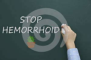 Little child writing phrase Stop Hemorrhoid on chalkboard, closeup