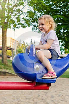 Little childplaying at playground in summer, sitting on carrousel