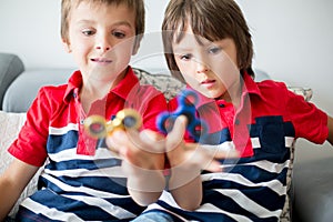 Little children, boy brothers, playing with colorful fidget spin
