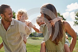 Little children, boy and girl enjoying piggyback ride on the back of their parents. Family spending time together in