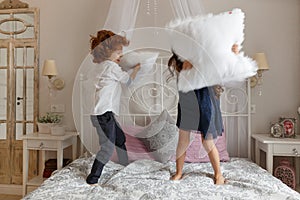 Little children, boy and girl fighting with pillows
