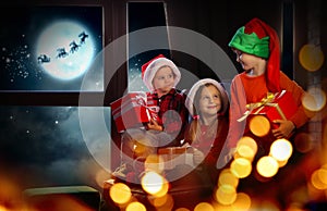 Little children with Christmas gifts near window. Presents from Santa Claus