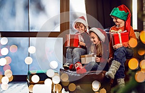 Little children with Christmas gifts near window. Presents from Santa Claus