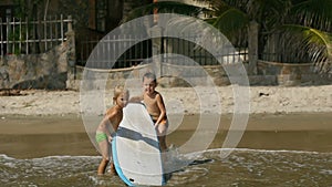 Little children enjoying sea surfboarding on summer vacation