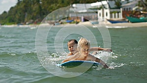 Little children enjoying sea surfboarding on summer vacation