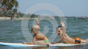 Little children enjoying sea surfboarding and waving hands in slow motion