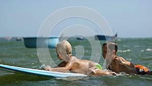 Little children enjoying sea surfboarding and waving hands in slow motion