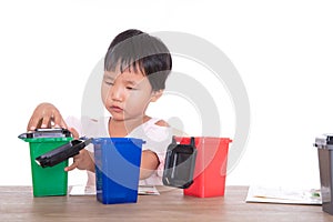 Little children in front of white background are playing sorting garbage bin model