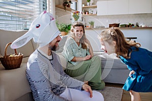 Little children having fun with her mother and father with Easter rabbit mask, celebrating Easter.