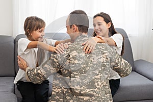 Little children hugging their military father at home