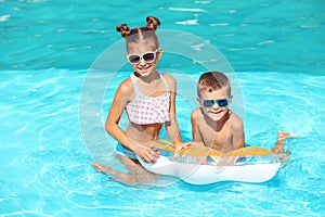 Little children with inflatable ring in swimming pool