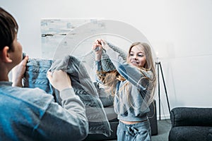 Little children in pajamas having pillow fight at home