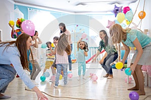 Little children and parents playing together on birthday party