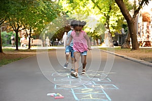 Little children playing hopscotch drawn