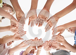 Little children putting their hands together indoors, view from below