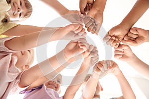 Little children putting their hands together indoors, view from below