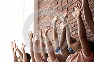 Little children raising hands together indoors