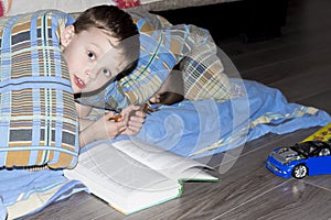 Little children are reading a book under blanket. Boy plays under blanket in house before bedtime.