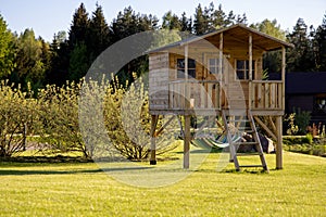 Little children`s tree house with a hammock in the garden on a sunny summer day