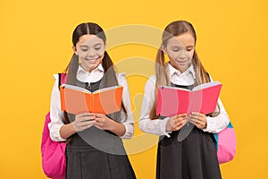 Little children in school uniforms read library books yellow background, reading