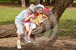 Little children sit on a tree in the park