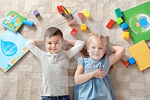 Little children with toys and books lying on carpet, top view. Playtime photo