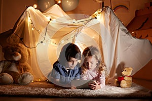 Little children using tablet in playroom