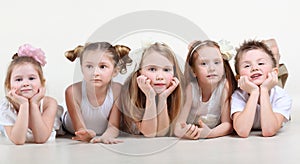 Little children in white clothes lie on floor