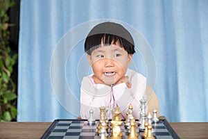 Little Chinese girl making cute faces in front of chess board
