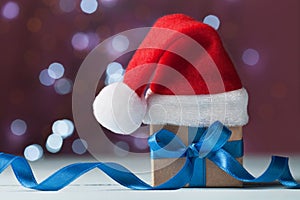 Little christmas gift box or present and santa hat against magic bokeh background. Holiday greeting card.