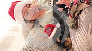 Little christmas girl and cocker spaniel puppy. Happy child in a santa hat holds a dog in his hands