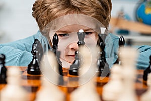 Little clever boy thinking about chess. Kids early development. Son are playing chess and smiling at home. Portrait