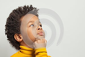 Little clever curious black child boy thinking on white background, close up portrait