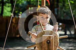 Little climber takes the rope bridge. Boy has fun time, kid climbing on sunny warm summer day