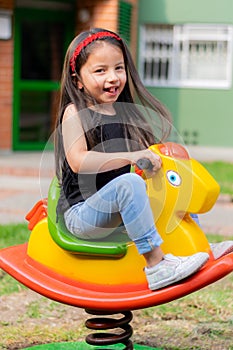 Little colombian girl plays in the park attractions in her backyard