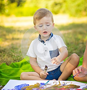 Little concentrated boy paint something in park